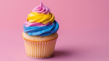 Multi-colored frosting on cupcake against pink background