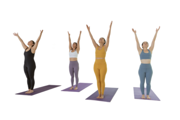 4 women practicing yoga in a studio raise their hands to make a pose