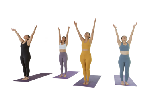 4 women practicing yoga in a studio raise their hands to make a pose