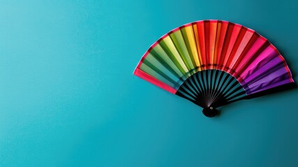 Colorful hand fan open against blue background