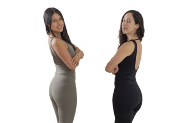 Two women in sportswear looking at the camera with their arms crossed and a manaste sign in the background