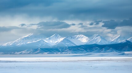 A winter landscape with snow-capped mountains in the distance, framed by a foreground of pristine white snow.
