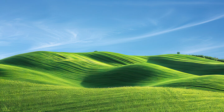 Emerald Green Hills of Tuscany: The rolling emerald green hills of Italy's Tuscany region provide a breathtaking view against the bright blue sky. This serene landscape evokes feelings of peace