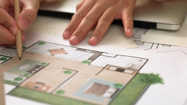 Professional engineer team discussion about house design on meeting table with architectural equipment and building blueprint scatter around at modern office. Focus on hand. Closeup. Delineation.