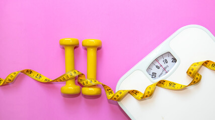 Weight loss control planning.  White scale and measuring tape with dumbbell for body dieting...