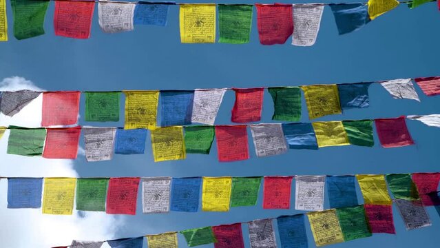 Colorful prayer flags against a blue sky at a Buddhist temple in northern India