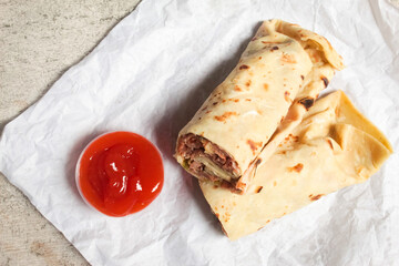 kebab with tortillas containing pieces of meat and spicy sauce