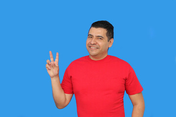 Dark-skinned Latino adult man makes the victory sign with his fingers happy and excited