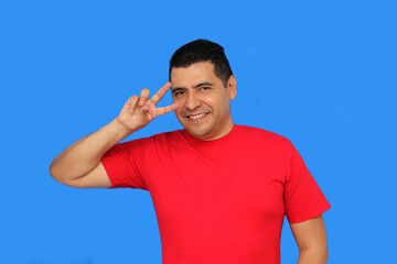 Dark-skinned Latino adult man makes the victory sign with his fingers happy and excited