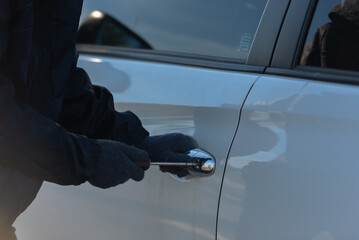 Close-up, Man dressed in a black holding screwdriver to break the lock and steal a vehicle on the...