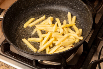 French fries are fried in oil in a frying pan
