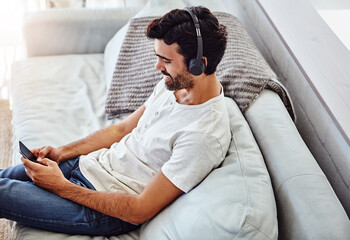 Home, man and cellphone with headphones on couch for listening to music, radio and networking....