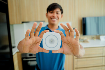 A technician installs a security alarm siren in a modern apartment.