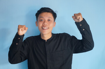 Fototapeta premium portrait of smiling happy asian young man with clenched fists