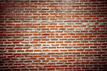A brick wall with a few missing bricks. The wall is brown and has a rough texture