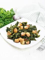 Kale cabbage with bacon in plate on white wooden board