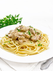 Meat in creamy sauce with spaghetti on table