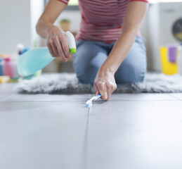 Woman cleaning the bathroom floor using a toothbrush