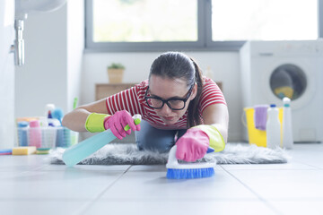 Obsessed woman cleaning the bathroom floor at home