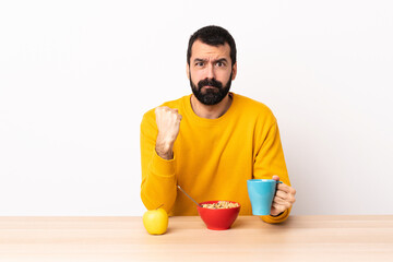 Caucasian man having breakfast in a table with unhappy expression.