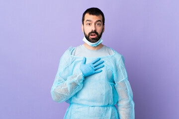 Surgeon man with beard with blue uniform over isolated purple background surprised and shocked while looking right
