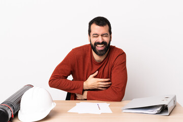 Caucasian architect man with beard in a table smiling a lot.