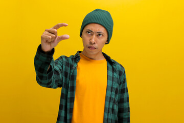 A displeased Asian man, dressed casually in a beanie hat and casual clothes, is gesturing a small...