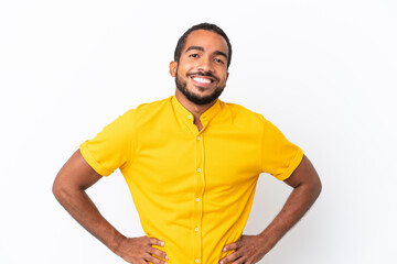 Young Ecuadorian man isolated on white background posing with arms at hip and smiling