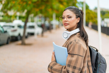 Young pretty woman at outdoors holding a notebook with happy expression