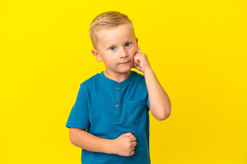 Little Russian boy isolated on yellow background thinking an idea