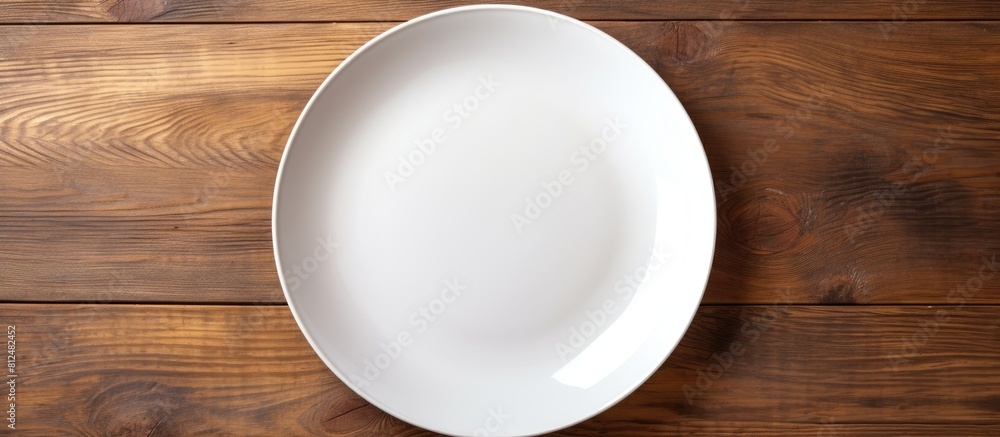 Poster Top view of an empty plate displayed on a wooden surface with ample copy space for images