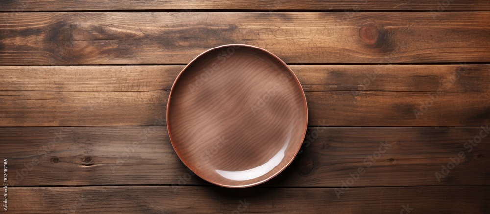 Poster Top view of an empty plate displayed on a wooden surface with ample copy space for images