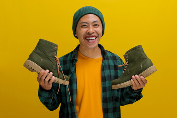 Happy Asian man, sporting beanie hat and casual shirt, joyfully unboxes a parcel package containing...