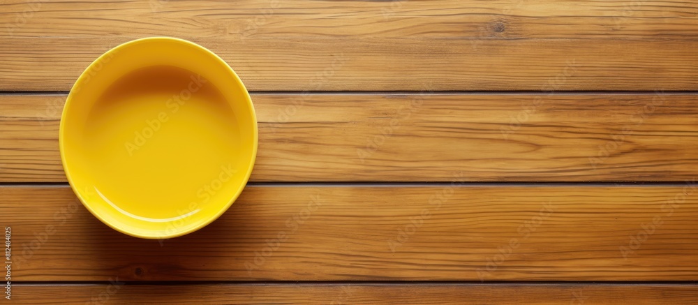 Poster copy space image available for design work with an empty yellow plastic dish and spoon on a wooden f
