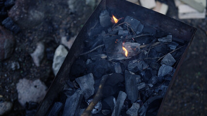 Handheld shot of charcoal in brazier, preparation for bbq