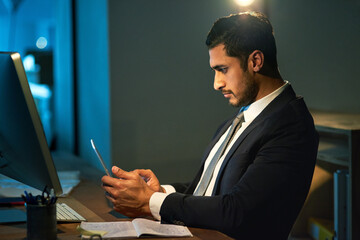 Businessman, office and phone by table at night for career, advocate or lawyer with research. Male person, computer and mobile by desk for work at law firm, plan for justice or court with technology