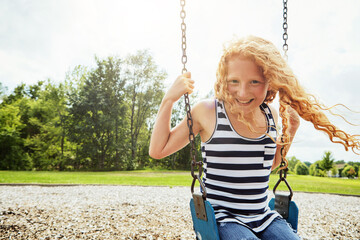 Child, portrait and smile with park, swing or nature for outdoor fun or play with fresh air. Girl, development and playground with summer, freedom and school holiday or break outside for happiness
