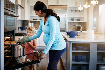 Obraz premium Mother, daughter and cookies in stove for baking in kitchen with learning, bonding and fun in home with teaching. Family, woman and girl with cooking dessert, cake and sweet snack by oven in house