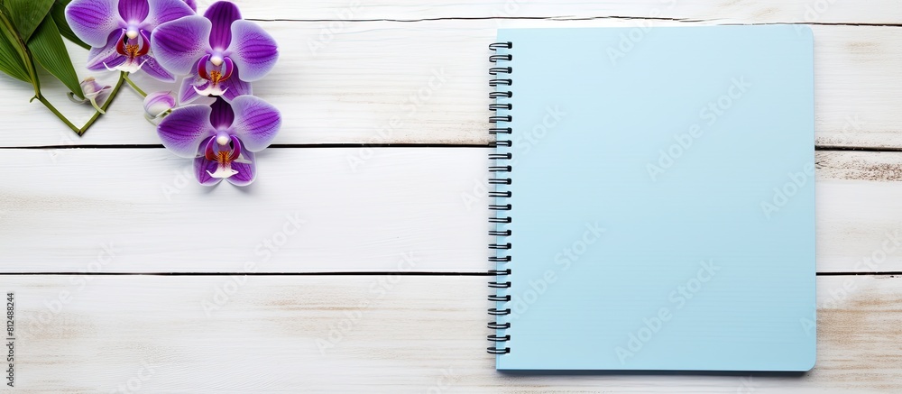 Poster A blue diary with colored pens and an orchid decoration on a white wooden surface perfect for a copy space image