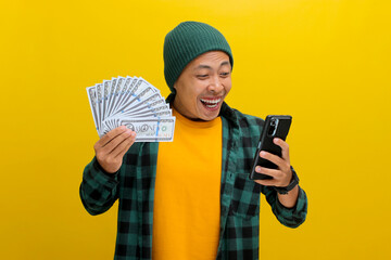 Excited Asian man wearing a beanie hat and casual clothes Examining his phone with a surprised...