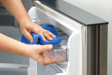 Employees use a cloth to clean the refrigerator.