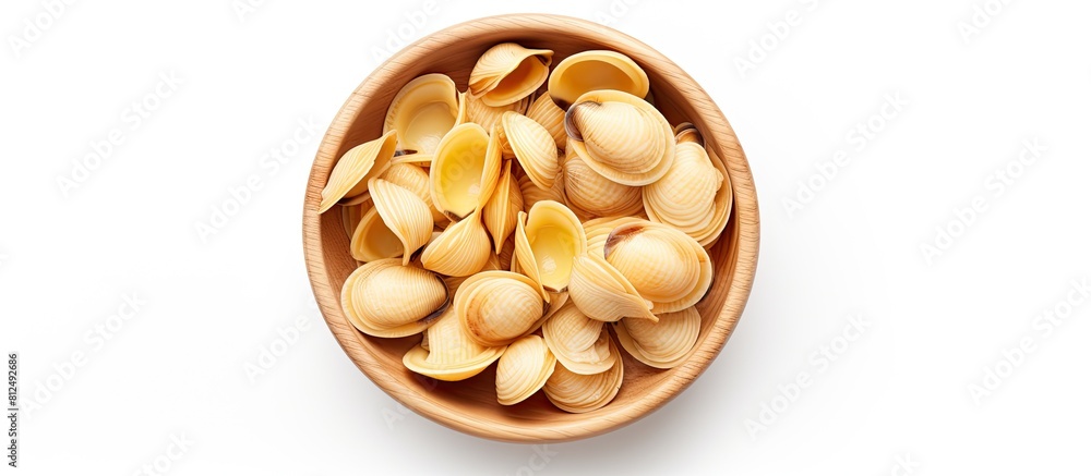 Poster Top view of a wooden bowl filled with raw striped shell pasta known as conchiglie rigate placed on a white background creating a perfect copy space image