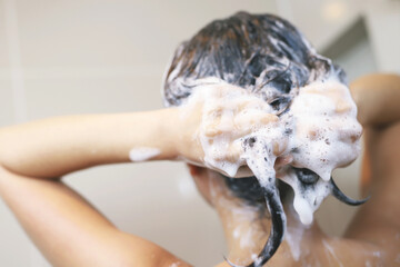 woman taking shower and washing hair with shampoo