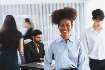 Young African businesswoman portrait poses confidently with diverse coworkers in busy meeting room...