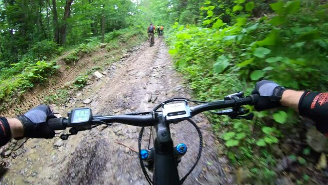 Point of view. Cyclists riding electric mountain bikes in the forest. Concept of adventure, leisure time outdoors.