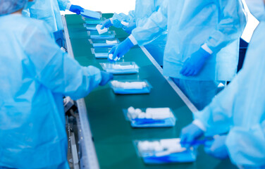 Worker in uniform collects tools into sterile kit surgical on conveyor belt. Pharmaceutical factory...