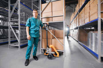 Caucasian industry man worker in blue uniform hold handle forklift in storage at medical products...