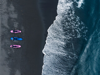 Group of friends surfers in wetsuit going to Extreme winter surfing in North ocean, aerial top...