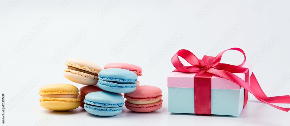 Poster a copy space image of colorful macaroons and a gift box placed against a white backdrop