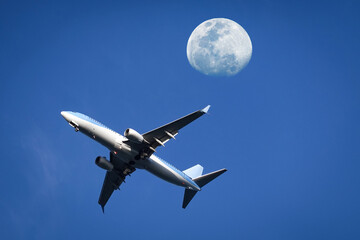 Airplane soaring through the moon on blue sky